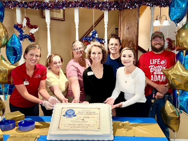 Staff and residents with a cake celebrating Autumn Ridge being named Jefferson County Leader Best Senior Living Community 2026